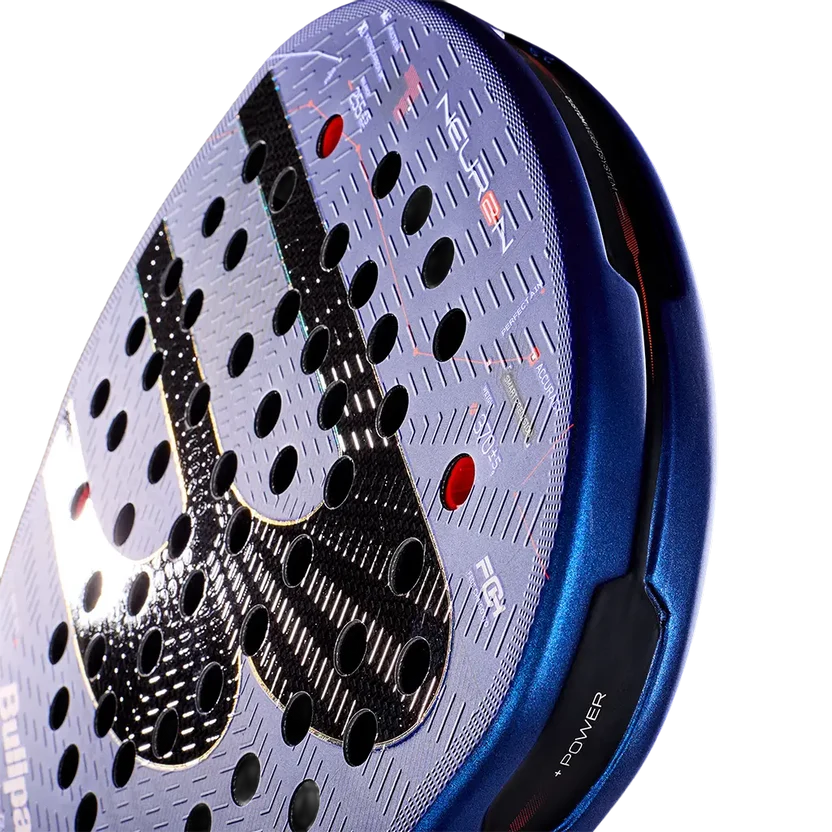 Detail slagoppervlak blauwe padel racket met een zwarte B op het slagoppervlak, oranje accent net boven het handvat en een zwart handvat.