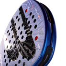 Detail slagoppervlak blauwe padel racket met een zwarte B op het slagoppervlak, oranje accent net boven het handvat en een zwart handvat.