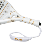Handvat witte Nox padel racket met gouden accenten in het logo.